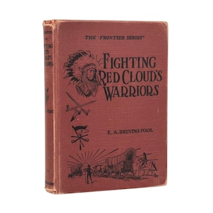 May include: A vintage, red-covered book titled "Fighting Red Cloud's Warriors" from "The Frontier Series." The cover features an illustration of a Native American chief in a headdress, crossed weapons, and a wagon train scene.