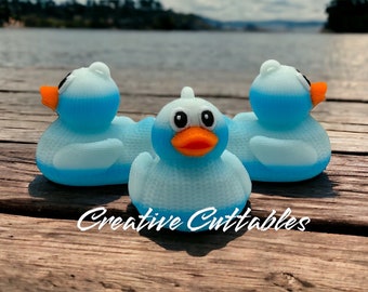 May include: Three blue rubber duck toys with orange beaks and white eyes. The ducks are sitting on a wooden surface. The ducks are slightly faded and have a textured surface.