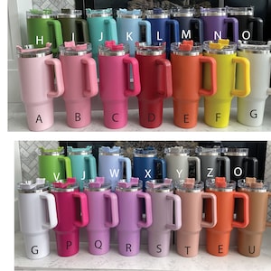 May include: A variety of colors of stainless steel travel mugs with handles. The mugs are arranged in two rows of 10. The colors include baby pink, bubblegum pink, hot pink, red, orange, yellow, white, green, olive green, teal, baby blue, royal blue, navy, purple, black, light green, sky blue, denim, light grey, grey, and khaki.