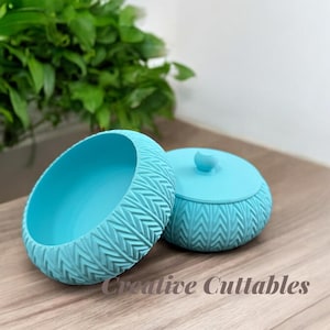 May include: Two turquoise decorative bowls with a textured, geometric pattern. One bowl is open, and the other has a matching lid with a small knob. The bowls are on a wooden surface, with the text "Creative Cuttables" in the image.
