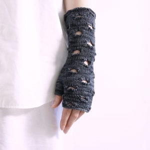 May include: Grey fingerless gloves with a lacy pattern. The gloves are knitted and have a loose fit.