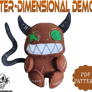 May include: A brown plush toy demon with a stitched-on green eye and a stitched-on green X over the other eye. The demon has a large stitched-on mouth with white teeth and a black tail. The toy is sitting on a white background. The text "INTER-DIMENSIONAL DEMON PDF PATTERN" is at the top of the image.