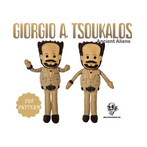 May include: Two felt dolls of Giorgio A. Tsoukalos, the Ancient Aliens personality, in a tan suit with a black belt and brown hair. The dolls have a mustache and beard. The text "GIORGIO A. TSOUKALOS" and "Ancient Aliens" are above the dolls. A "PDF PATTERN" label is on the left.