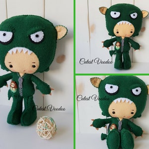 May include: Green felt monster costume for a plush toy. The costume has a zipper down the front and a small felt monster on the pocket. The text "Cutest Voodoo" is visible on the image.