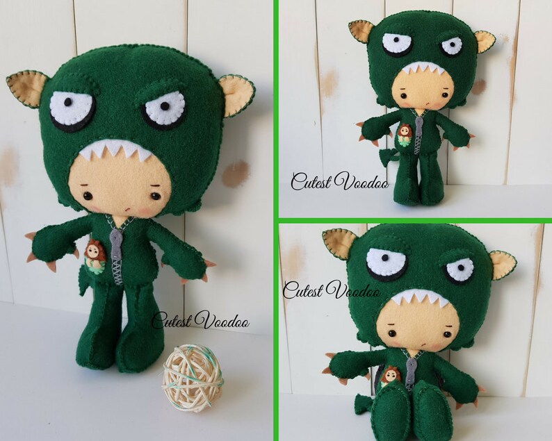 May include: Green felt monster costume for a plush toy. The costume has a zipper down the front and a small felt monster on the pocket. The text "Cutest Voodoo" is visible on the image.