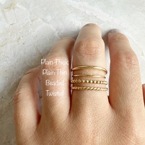以下が含まれることがあります： 指に重ねられた4つの金のリング。リングには「Plain Thick」、「Plain Thin」、「Beaded」、「Twisted」とラベルが付けられています。