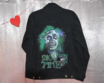 Könnte beinhalten: Schwarze Jeansjacke mit einer farbenfrohen Grafik eines Charakters mit grünen Haaren und den Worten "SHOW TIME". Die Jacke hat eine Knopfleiste und goldfarbene Knöpfe. Ein Halloween-Themenartikel.