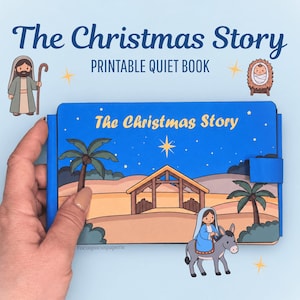 Pode incluir: Um livro silencioso azul intitulado The Christmas Story com uma ilustração de desenho animado de uma paisagem desértica com um estábulo, palmeiras e uma figura montada num burro. A capa exibe o texto The Christmas Story em amarelo.