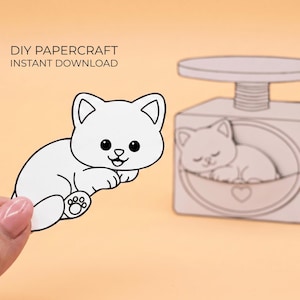 Könnte beinhalten: Ein DIY-Papierbastel-Sofort-Download mit einem weißen Katzen-Ausschnitt mit schwarzen Umrissen und einer passenden Papier-Kratzbaumstruktur mit einer schlafenden Katzenillustration und einem Herzdetail. Text DIY PAPERCRAFT INSTANT DOWNLOAD.