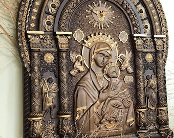 May include: A carved wooden icon of the Virgin Mary and baby Jesus, with a gold-leaf background and intricate details. The icon is framed in a dark wood with gold accents and features a carved archway.