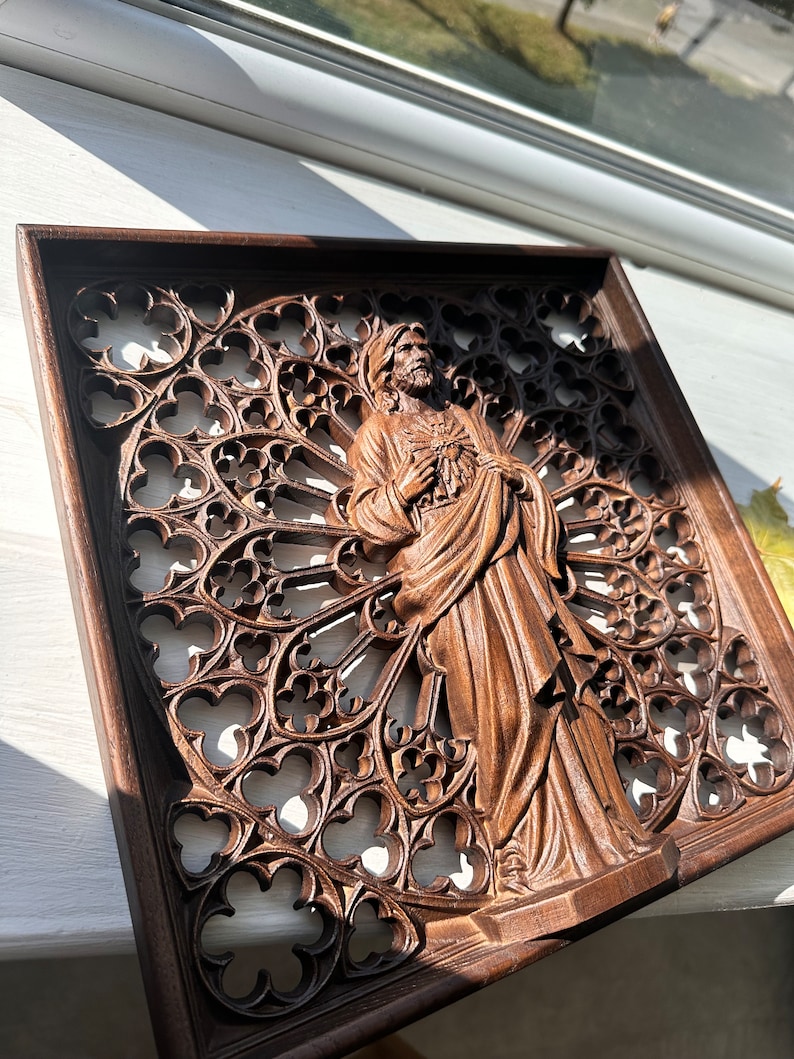 Puede incluir: Una escultura de pared de madera de una figura religiosa con un coraz&oacute;n en la mano, tallada en un estilo g&oacute;tico detallado.