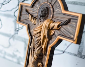 May include: A wooden cross with a gold-painted Jesus figure, surrounded by a halo and rays of light. A dove with gold wings is depicted above Jesus.