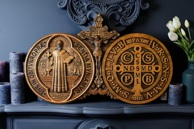 May include: Two wooden plaques with religious imagery. The left plaque features a depiction of Saint Benedict with the words "EIVS IN OBITVNRO PR&AElig;" and "EX SM CASINO MDCCCLXXX". The right plaque features a depiction of the Saint Benedict Medal with the words "PAX" and "V.R.S.N.S.V.B.B.V.I.T.O.M.N.S.S.M.W."