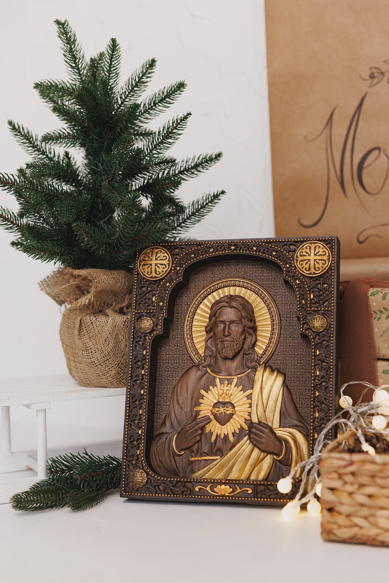K&ouml;nnte beinhalten: Eine rechteckige Wandtafel aus Holz mit einem Reliefschnitzwerk des Heiligsten Herzens Jesu. Die Figur ist mit langem Haar, Bart und einem goldenen Heiligenschein dargestellt und h&auml;lt ein flammendes Herz. Der Rahmen hat detaillierte Schnitzereien.