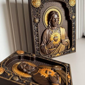K&ouml;nnte beinhalten: Zwei rechteckige Wandtafeln mit einem Relief von Jesus Christus mit dem Heiligsten Herzen. Die dunkelbraunen, holzfarbenen Figuren sind mit goldener Farbe am Heiligenschein und am Herzen akzentuiert. Die verzierten Rahmen haben filigrane Details.