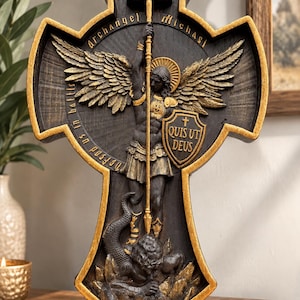 May include: A black and gold wall plaque shaped like a cross featuring Archangel Michael holding a sword and a shield with the text "Quis Ut Deus". The figure stands over a serpent, with the text "Defend us in battle" and "Archangel Michael" inscribed.