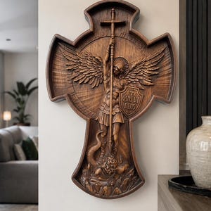 May include: A dark brown wooden wall plaque shaped like a cross, featuring a detailed relief carving of Saint Michael the Archangel defeating a serpent. The figure holds a long sword and a shield inscribed with the Latin text, "QUIS UT DEUS."