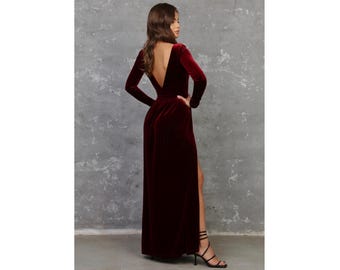 May include: A long, burgundy velvet dress with a deep V-neckline and a thigh-high slit. The dress has long sleeves and a fitted bodice.