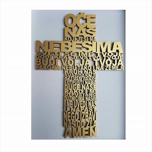 Puede incluir: Una cruz de madera dorada con la oración del Señor escrita en idioma croata. Las palabras están dispuestas en forma de cruz.