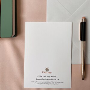 The back of the postcard shows the designer's logo and contact details.
The photo also shows a white envelope that is included.