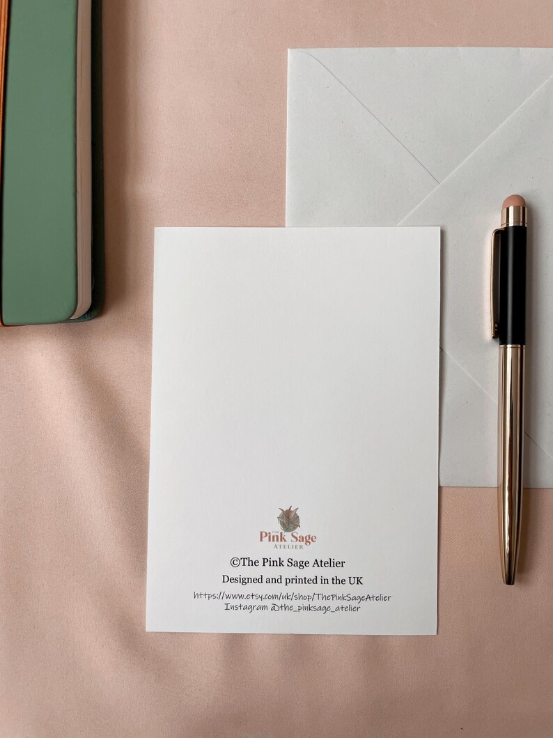 The back of the postcard shows the designer's logo and contact details.
The photo also shows a white envelope that is included.