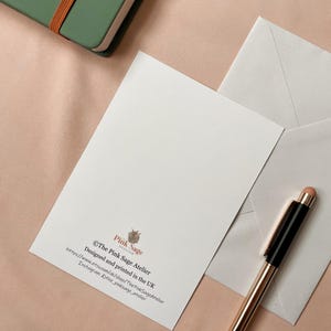 The back of the postcard shows the designer's logo and contact details.
Also shows a white envelope that is included.