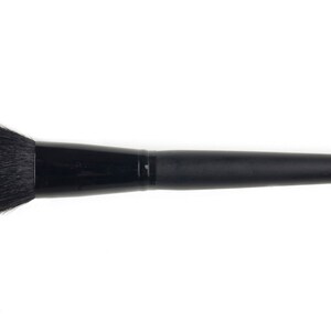 May include: A black makeup brush with a round, fluffy head and a long, black handle.