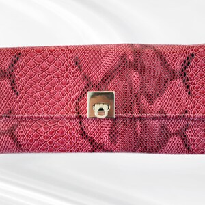 May include: A pink snakeskin clutch with a silver clasp.