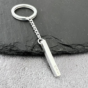 May include: Silver keychain with a bar charm engraved with the name "Max".