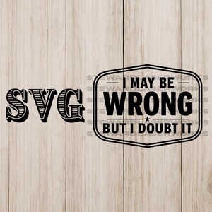 Op de afbeelding: Zwart SVG-ontwerp met de tekst "I MAY BE WRONG BUT I DOUBT IT" in een kader. Het woord "SVG" is ook in zwart, met een decoratief lettertype. De achtergrond is een lichte houtnerf.