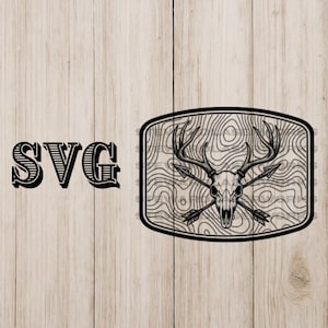 May include: Black and white graphic design featuring a deer skull with crossed arrows inside a rectangular frame. The word "SVG" is printed in a bold, stylized font to the left of the frame. The background is a light wood grain.