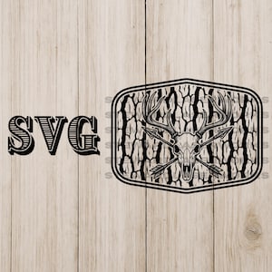 Puede incluir: Diseño SVG en blanco y negro con una calavera de ciervo con flechas cruzadas, dentro de un marco rectangular texturizado. La palabra "SVG" se muestra en una fuente decorativa y en negrita. Fondo de vetas de madera clara.