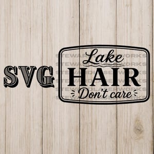 Op de afbeelding: Zwart-wit SVG-ontwerp op een lichte houtnerf achtergrond. Het ontwerp bevat het woord "SVG" aan de linkerkant en een rechthoekig frame met de woorden "Lake Hair Don't Care" erin.