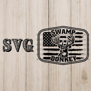 May include: Black and white graphic design featuring a deer with large antlers, set against a stylized American flag background. The text "SWAMP DONKEY" is displayed below the deer. The letters "SVG" are on the left.
