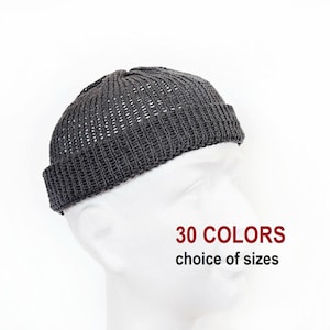 May include: A dark gray knit beanie with a rolled cuff and a textured, open-stitch pattern on the crown. The text 30 COLORS choice of sizes is displayed in red and black lettering on the right side of the white mannequin head.