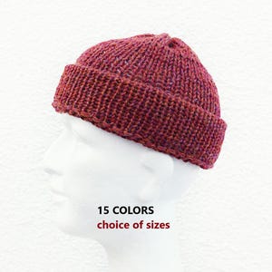 Könnte beinhalten: Eine bordeauxrote Strickmütze mit einem dicken umgeschlagenen Rand aus strukturiertem Garn. Der Text 15 COLORS choice of sizes ist in Schwarz und Rot unter der Mütze aufgedruckt. Die Mütze wird auf einem weißen Schaufensterpuppenkopf vor weißem Hintergrund gezeigt.