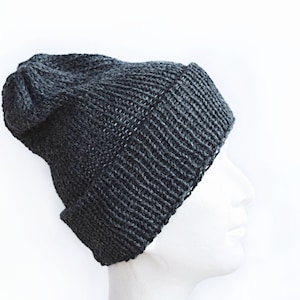 K&ouml;nnte beinhalten: Eine dunkel anthrazitfarbene Strickm&uuml;tze mit geripptem Umschlag und einer leicht locker sitzenden Krone. Die M&uuml;tze ist aus dickem Garn mit einem sichtbaren Strickmuster gefertigt und verf&uuml;gt &uuml;ber einen umgeschlagenen Rand.