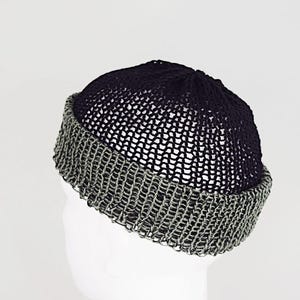Könnte beinhalten: Eine zweifarbige Mütze mit einer schwarzen Krone in offener Strickstruktur und einem breiten, umgeschlagenen Rand in kontrastierendem Grau. Die Mütze ist mit einem sichtbaren, lockeren Maschenmuster gefertigt, das ein leichtes und luftiges Erscheinungsbild erzeugt.