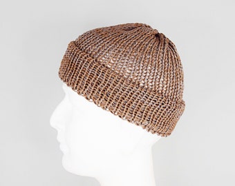May include: A brown knit beanie with a distinct ribbed texture and a folded cuff. The hat features a consistent, open-loop stitch pattern throughout the crown and the brim, creating a structured, rounded silhouette that sits firmly on the head.