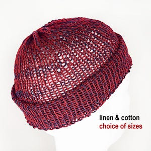 Könnte beinhalten: Eine bordeauxrote und dunkelblaue Strickmütze mit umgeschlagenem Rand und einer grobmaschigen Struktur. Der Text linen & cotton choice of sizes ist in Schwarz und Rot unter der Mütze aufgedruckt. Die Mütze liegt auf einem weißen Kopfmodell.