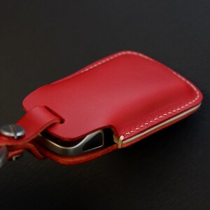 May include: Red leather key fob with white stitching and a metal key ring.