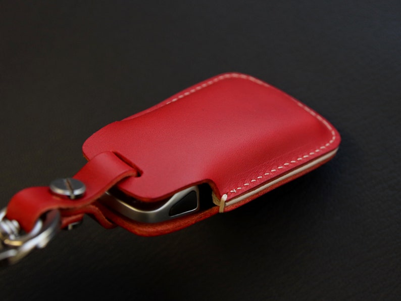 May include: Red leather key fob with white stitching and a metal key ring.
