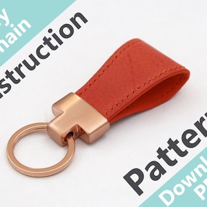 May include: A red leather keychain with a rose gold metal ring and a loop. The text "Key Chain Instruction Pattern Download PDF" is visible in the background.