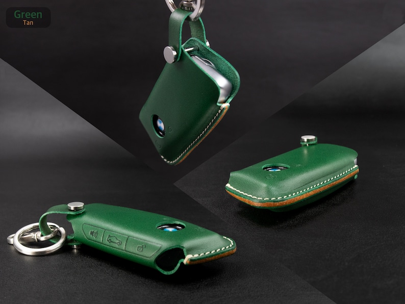 May include: Green leather key fob with tan stitching and a silver key ring. The fob has a BMW logo and buttons for locking, unlocking, and trunk release.