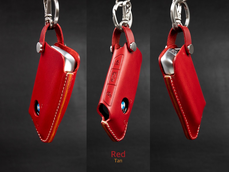 May include: Red leather key fob with a tan stitching detail. The fob has a silver metal loop and a silver metal snap closure.