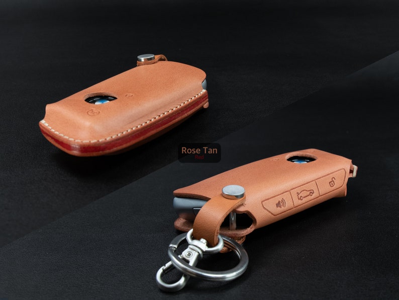 May include: Two leather key fobs in rose tan color. One fob is closed and the other is open with a silver key ring attached. The open fob has a car icon and a lock icon embossed on it.