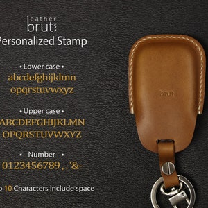 May include: A brown leather key fob with a stitched edge and the word "brut" embossed on the front. The fob has a silver key ring attached. The image shows a personalized stamp option with lowercase and uppercase letters, numbers, and symbols. The text reads "Up to 10 Characters include space".