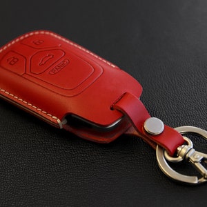 May include: Red leather key fob with a silver key ring and a key chain. The fob has a stitched edge and the text "PANIC" is visible on the key fob.