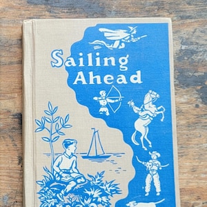 May include: A vintage book cover with a blue background and the title "Sailing Ahead" in white text. The cover features illustrations of a boy sitting by a lake, a sailboat, a horse, a cowboy, a dog, and a fairy.