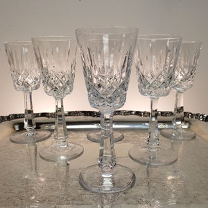 May include: Six clear glass wine glasses with a diamond pattern on a silver tray.